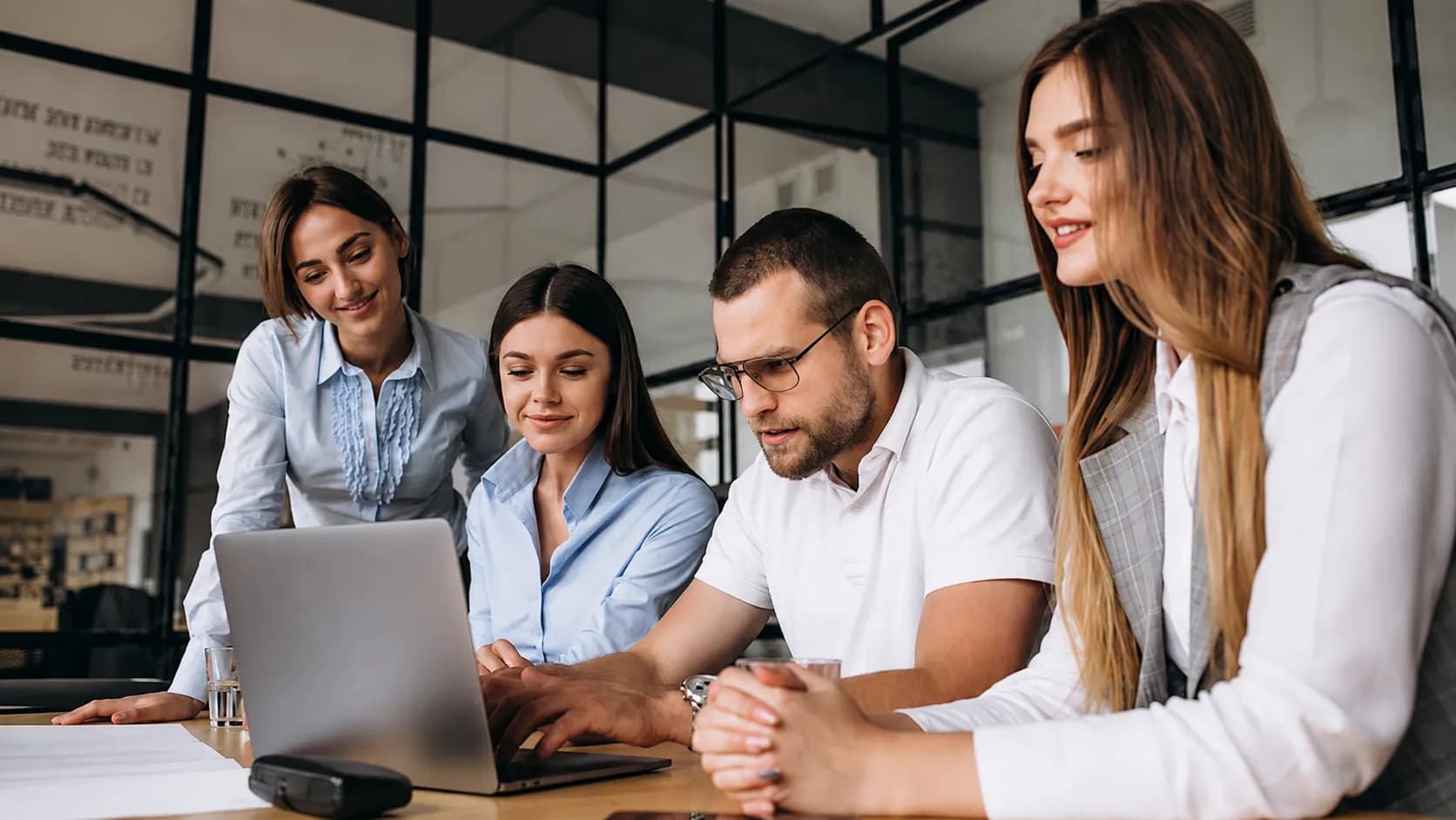 Cuatro personas trabajando juntas alrededor de una notebook en una oficina